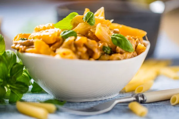 Pasta penne com pedaços de frango cogumelos manjericão e queijo parmesão Comida italiana em tigela branca na mesa da cozinha — Fotografia de Stock