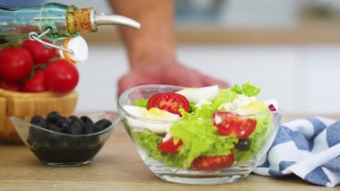 İnsan mutfağındaki taze sebze salatasına zeytinyağı döker. Ham formatta Siyah Sihirli Sinema 6k kamerasında yavaş çekim.