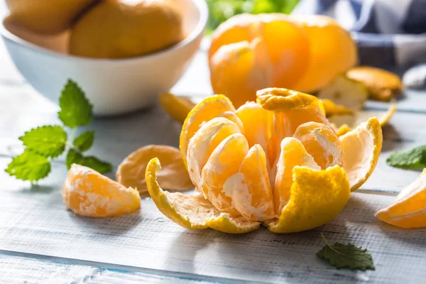 Tangerinas com casca e mellisa ervas na mesa. Fruta tropical fresca madura em tábua de madeira — Fotografia de Stock