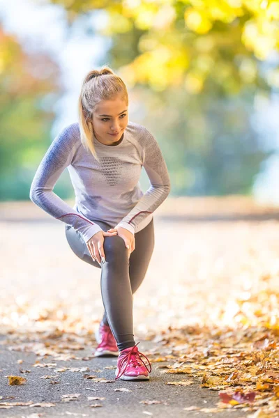 Mujer deportista joven haciendo estiramiento o calentamiento del cuerpo a — Foto de Stock