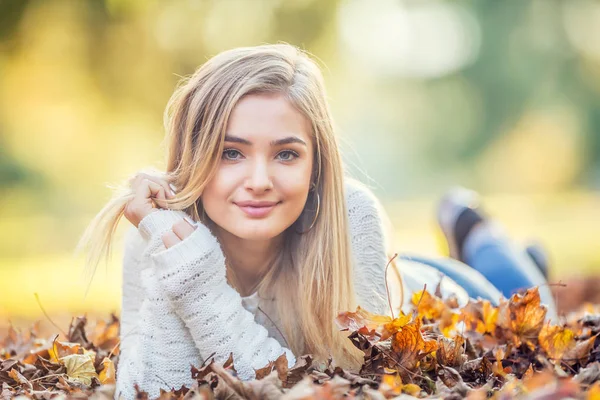 Retrato de otoño de una joven acostada sobre hojas de arce en el parque —  Fotos de Stock