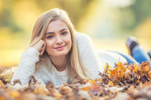 Herfst portret van jonge vrouw liggend op esdoorn bladeren in park — Stockfoto