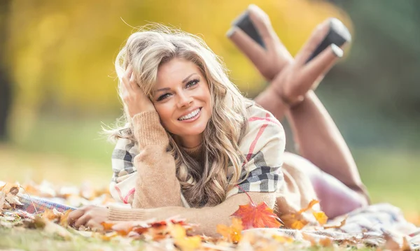Jovem atraente com sorriso sensual encontra-se no parque de outono — Fotografia de Stock