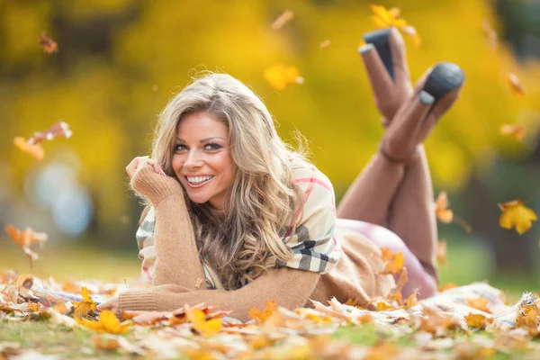 Ελκυστική νεαρή γυναίκα με αισθησιακό χαμόγελο βρίσκεται στο πάρκο φθινόπωρο — Φωτογραφία Αρχείου