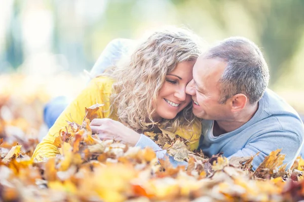 Glada äldre par ligger i höst lönnlöv — Stockfoto