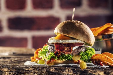 Köy ortamında kızarmış yumurta, pastırma, marul ve patates dilimleri ile hamburger.