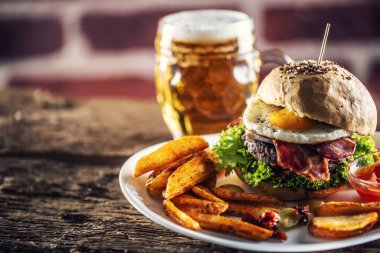 Susamlı hamburger, sahanda yumurta ve pastırma, salata ve patates dilimleri.