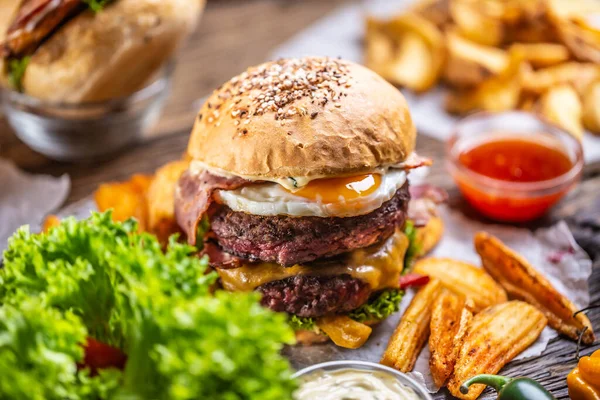 Double beef bacon burger with cheese and lettuce, potato chips and salsa on a side