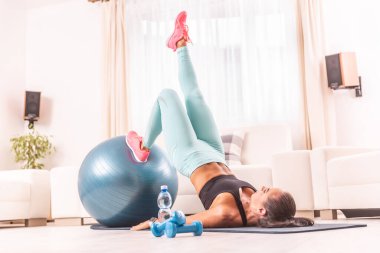 Kadın evde çalışıyor, çekirdeğini yerden kaldırıyor, bir bacağı esnemiş, bir bacağı da formda..