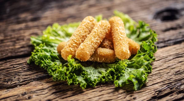 Detail of fried mozzarela sticks on a green leaf placed on rustic wood table — Stock Photo, Image