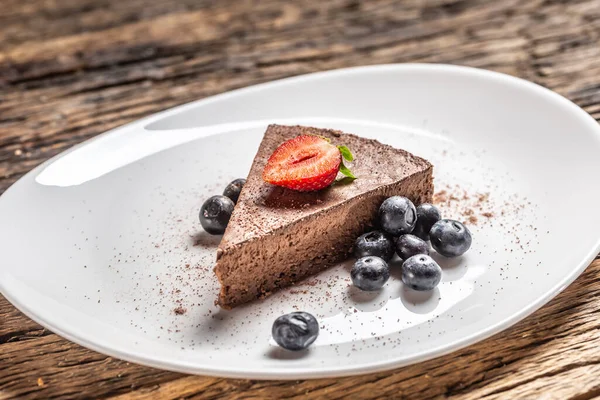 Rebanada triangular de un pastel de mousse de chocolate con arándanos y fresas — Foto de Stock