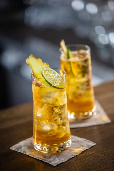 Два бокала виски и имбирный лимонад со льдом и ломтиками свежего имбиря и лайма — стоковое фото