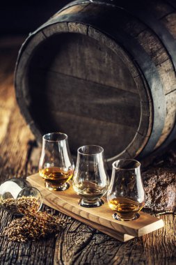 Glencairn yanında ahşap fıçı, turba ve arpa olan viski bardaklarını tadıyor.