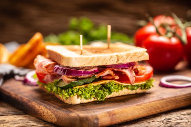 Kesme tahtasında soğanlı BLT sandviçi.