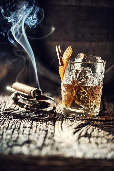 Whisky with no ice in a cup with burning cigar and an old wooden barrel in the background — Stock Photo, Image