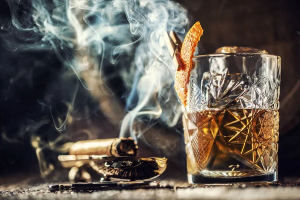 Whisky with no ice in a cup with burning cigar and an old wooden barrel in the background — Stock Photo, Image