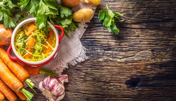 Caldo de sopa de pollo en un tazón vintage con fideos caseros cebolla zanahoria apio hierbas ajo y verduras frescas . —  Fotos de Stock