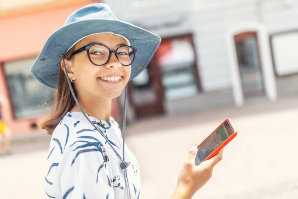 Młoda Dziewczyna Uśmiechnięta Kamery Telefonem Komórkowym Ręku Chodząca Ulicą — Zdjęcie stockowe