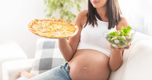 Menina Grávida Sentado Sofá Segurando Tigela Salada Uma Mão Pizza — Fotografia de Stock