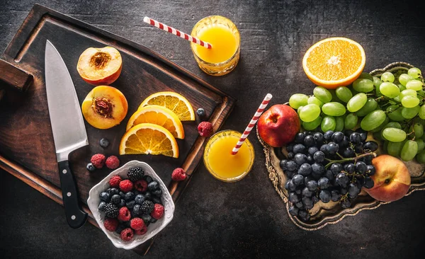 Top of view φρέσκα φρούτα χυμός πορτοκαλί σταφύλια ροδάκινο μούρα στο τραπέζι του σκυροδέματος — Φωτογραφία Αρχείου