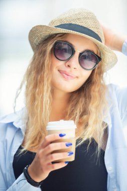 Genç şık sarışın kahve içiyor gülümsemek ve sokakta yürümek için..