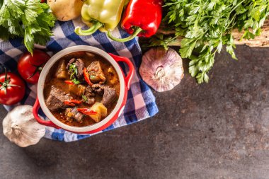 Et, patates ve biberli bir kase gulaş çorbası güveç için ham malzemelerin yanında..