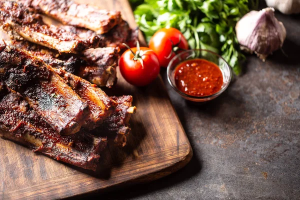 Baked glazed bbq ribs with a tomato sauce on the side.