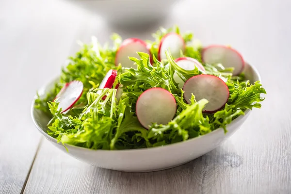 Skål av en sallad blad med skivad utstrålade placeras på ett bord — Stockfoto