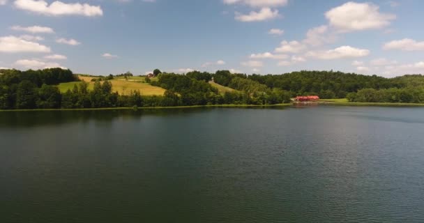 Вид с воздуха на холмы и дом на озере и док с лодками — стоковое видео