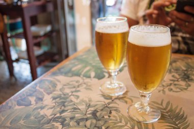 Light bira köpük bir cam bar tablo. Tam cam ve bulanık arka planını bar ve adamın elleri ile telefon. Metin için boş alan