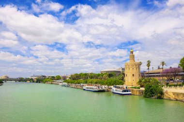 Nehir Guadalquivir güzel görünümünden için altın kule Torre del oro güneşli yaz gün, mavi gökyüzü ve beyaz bulutlar