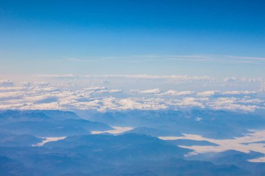 Güzel mavi gökyüzü beyaz dokusal bulutlar ve güneşli gün dağlarda, uçak penceresinden görüntülemek