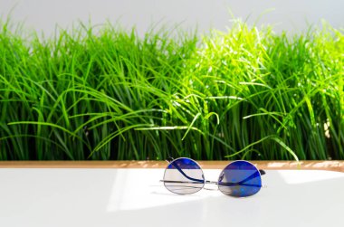 Kopya alanı parlak yeşil çim zemin üzerine beyaz masada modern mavi güneş gözlüğü.