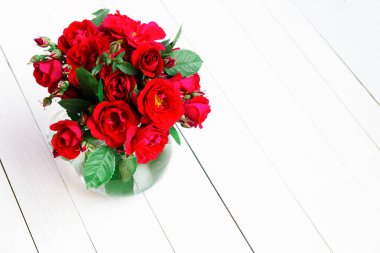 Ev gül cam vazoda Beyaz ahşap bir masa üzerinde. Kopya alanı ile