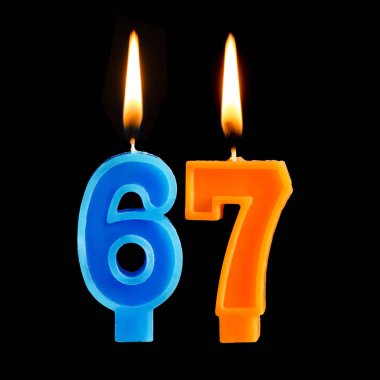 Yanan Doğum günü mumları 67 altmış yedi için siyah arka plan üzerine izole pasta şeklinde.