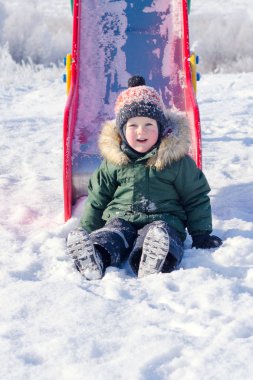 Kışın Oyun Alanı'nda kızağa binen çocuk