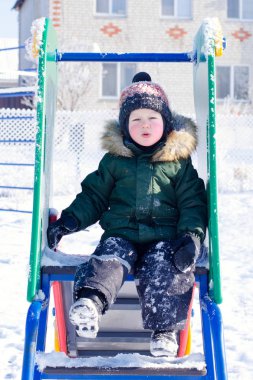 Kışın Oyun Alanı'nda kızağa binen çocuk