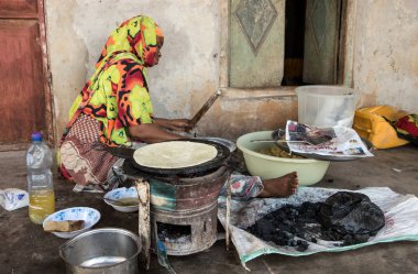 Zanzibar, Tanzanya, Doğu Afrika - 20 Haziran 2017: bir Afrikalı kadın flatbreads bir ocakta kömür ile geleneksel ekmek kek - pişirme. 