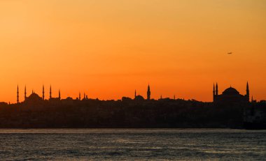 Günbatımı boğaz. Sultanahmet Camii ve Ayasofya'nın siluetleri üzerinde uçak çıkartıyor. Istanbul, Türkiye.