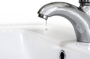 Bir damla su karşı beyaz bir Lavabo Bataryası. Su sızıntı ve kaydetme.