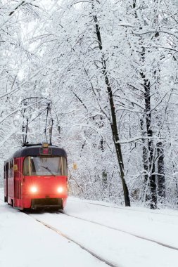 Eski kırmızı tramvay ile karlı ormanın içinden gidiyor. Kış arsa. Seçici odak