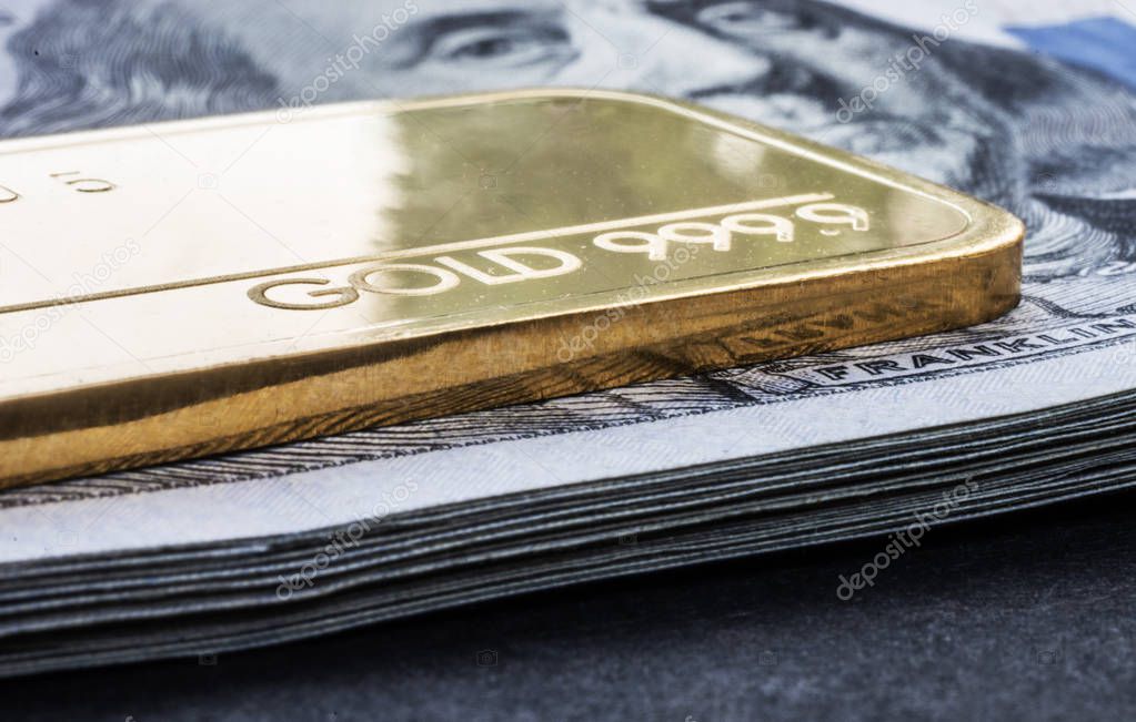 Minted gold bar weighing 50 grams 999.9, fineness against the background of a dollar bills.