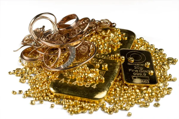 A pile of gold bars, gold jewelry and gold granules. Isolated on white background. Selective focus.