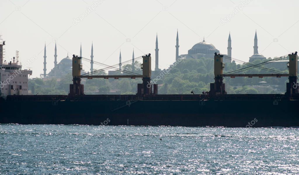 Silhouette of a bulk carrier sailing along the Bosphorus, against the background of the Blue Mosque and Hagia Sophia. Istanbul, Turkey.