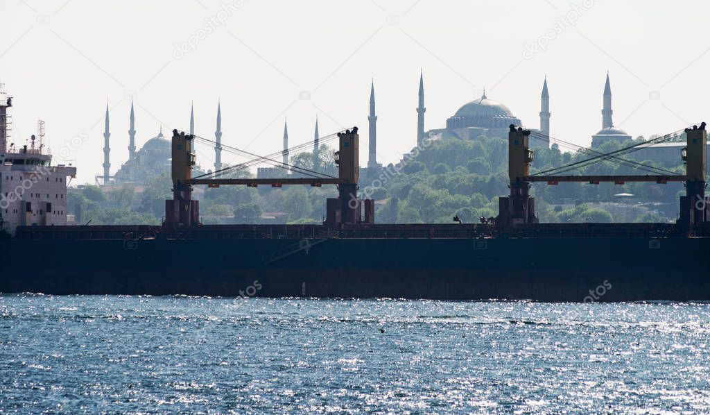 Silhouette of a bulk carrier sailing along the Bosphorus, against the background of the Blue Mosque and Hagia Sophia. Istanbul, Turkey.