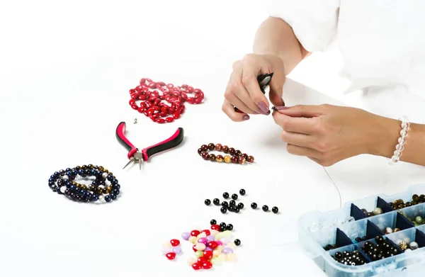 Jewelry making. Female hands with a tool on a white background.