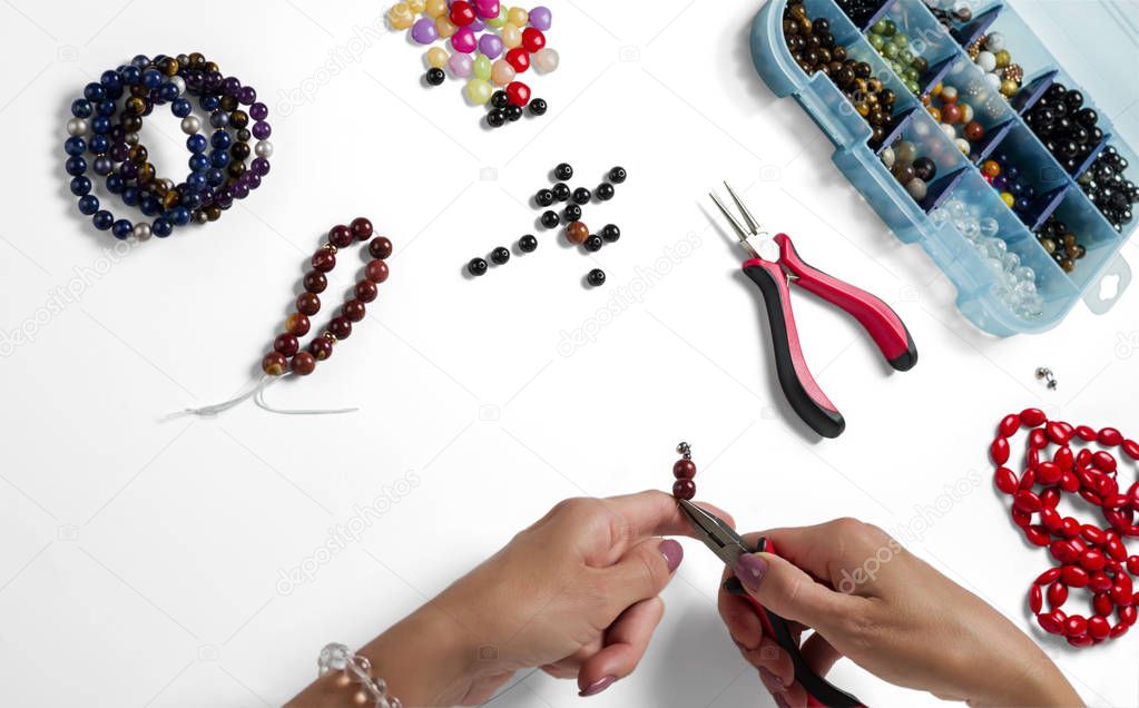 Jewelry making. Production bracelets and necklaces from multi-colored beads on a white background