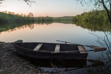 Gün batımında nehir kıyısında kürekli tekne. Seçici odaklama.