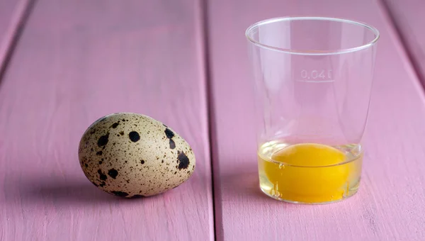 Quail eggs in the shell and in a measuring glass.