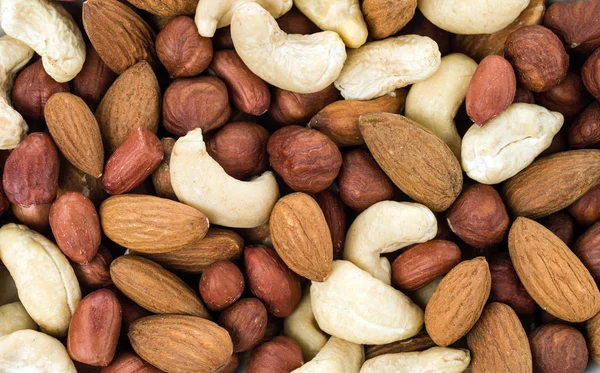 Background from a mixture of four types of nuts: cashews, peanuts, hazelnuts, and almonds.